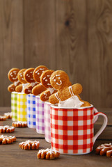 Gingerbread in the form of little men in colorful cups on wooden background.