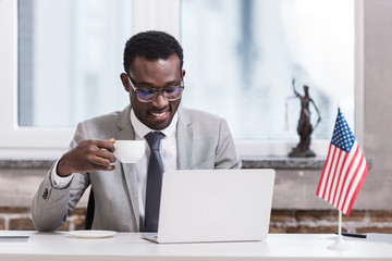 African american businessman drinking coffee and using laptop