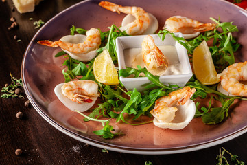 The concept of Italian cuisine. Tiger prawns on rice chips in a creamy sauce. Arugula salad and lemon. On the table is a glass of red wine. beautiful serving in the restaurant