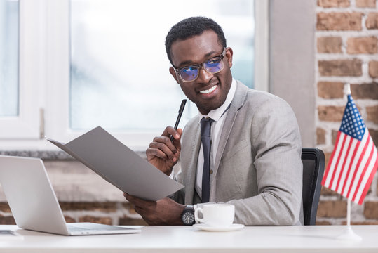 African American Businessman Holding Folder And Pen In Office