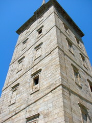 Interested view from the bottom at the foot of the ancient medieval beacon on its grandeur on the background of the blue sky.