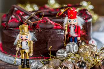 A wooden toy soldier ornament is standing next to cherry chocolate Christmas cake