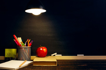 The teacher's desk or a worker, on which the writing materials lie, a book and an apple, in the...