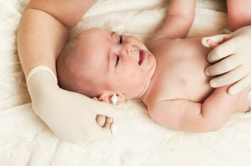 The child at the doctor's office and his ears are cleaned with a cotton swab.