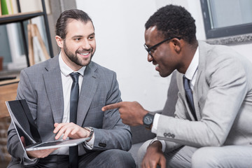 african american businessman pointing with finger at business partners laptop in office