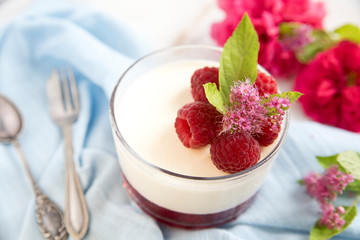 Great panacotta dessert with raspberries, on a blue background and vintage spoon and fork. Retro .