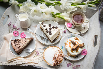 Table with loads of coffee, cakes, cupcakes, desserts, fruits, flowers and croissants. Ancient spoons and a tray, a table in a vintage style.