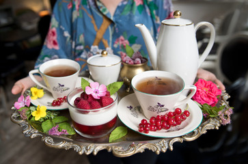 Magnificent fresh hot tea in ancient cups on a silver vintage tray and a raspberries dessert, an antique teapot