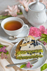 A cup of tea, a teapot and a piece of spinach cake on a table in light colors in retro style