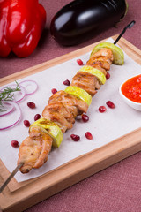 Grilled meat on metal skewer served with sauce