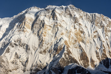 Close-up impressive view of Annapurna 1 summit against clear blue sky during sunrise ( golden hour) in the Himalayas