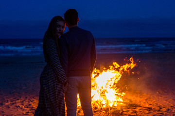 Romantic mature couples watch the sea in front of campfire at night
