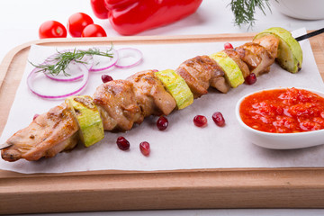 Grilled meat on metal skewer served with sauce