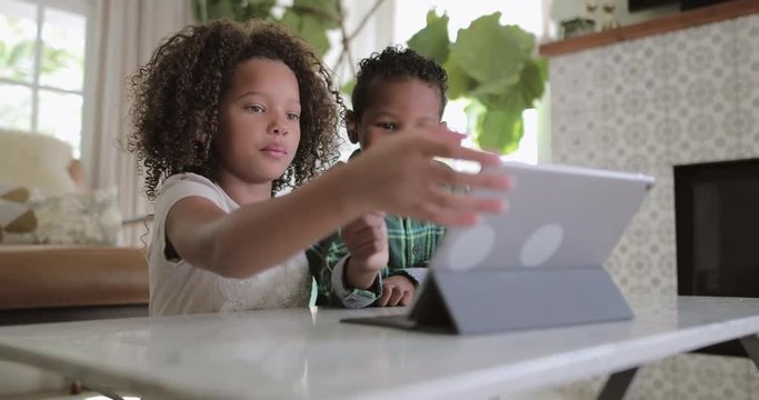 African American brother and sister playing together on digital tablet