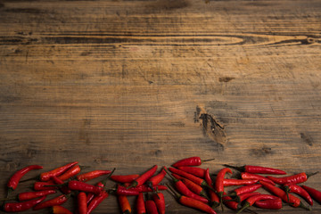 Red chili pepper on a vintage plate, dried chillies on wooden background. Top view. Copy spase.