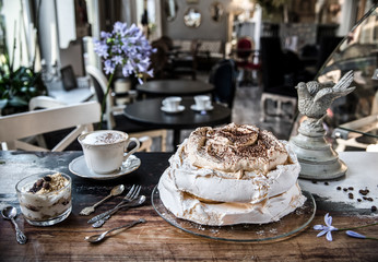 Cake-meringue, dessert and latte coffee on a vintage table in a cafe in a retro style