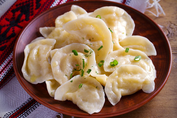 Dumplings, filled with mashed potato in plate on wooden table. Varenyky, vareniki, pierogi, pyrohy - dumplings with filling. Vegetarian dish. horizontal