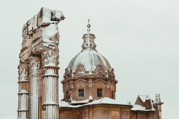 Fototapeta na wymiar Frozen Rome. Baroque Church and pagan temple ruins covered by snow, a very rare event in the city