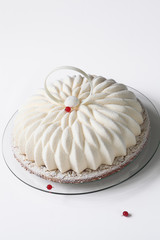 Piece of Contemporary Vanilla Red Currant Mousse Cake covered with white velvet spray, on white background.