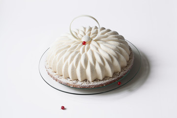 Piece of Contemporary Vanilla Red Currant Mousse Cake covered with white velvet spray, on white background.