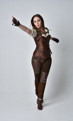 full length portrait of brunette  girl wearing brown leather steampunk outfit. standing pose on...