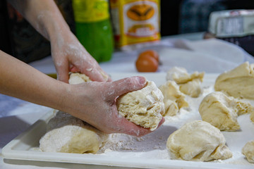 Woman's hands work with dough in the kitchen. Kneading homemade dough with flour for bread, pastry or pizza.