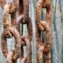 Rusty metal chains on the wooden background