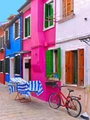 Fototapeta na wymiar Burano, Italy. View of the colorful houses with windows, laundry cloths to dry outside and bicycle in the small picturesque island of Burano near 