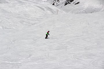 girl in a colorful suit is on a snowboard rides with mountains