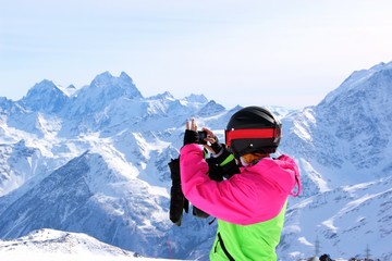 Fototapeta na wymiar girl in a colorful suit photographed on top of a snowy mountain
