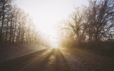 Obraz premium Winter foggy morning golden sunrise with road