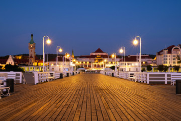 A long wooden pier in Sopot, Poland, with a view of the lighthouse - obrazy, fototapety, plakaty
