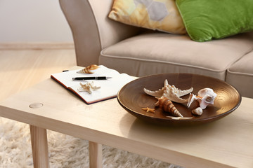 Different sea shells with starfish on wooden table in interior of room
