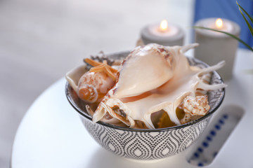 Bowl with different sea shells on white table