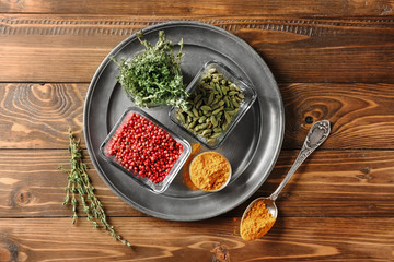 Bowls with different aromatic spices and thyme on metal tray