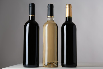Bottles with different kinds of wine on grey background
