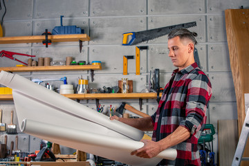 A carpenter works. Carpenter studying drawing project. Against the background of the workshop