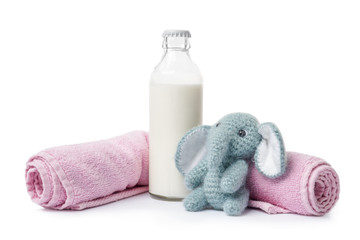 Obraz na płótnie Canvas Bottle of milk with towels and toy on white background