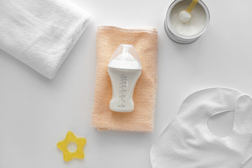 Feeding bottle of baby formula with powder and towels on white background