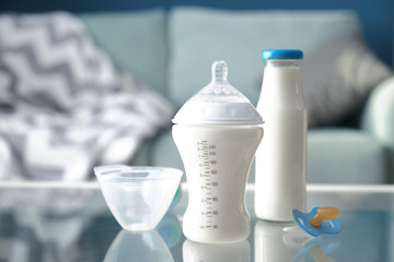 Bottles of baby formula with pacifier on glass table