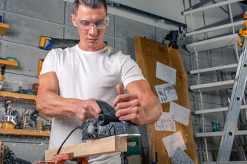A carpenter works on woodworking the machine tool. Saws furniture details with a circular saw....