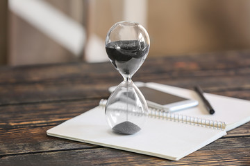 Hourglass on open notebook. Time management concept