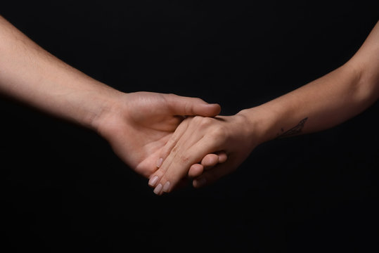 Man and woman holding hands on dark background