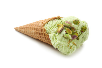 Waffle cone with delicious ice cream and pistachios on white background