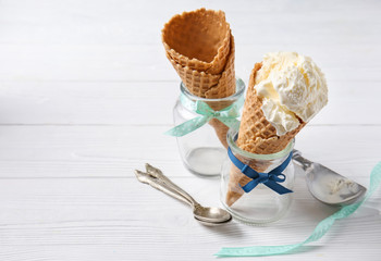 Waffle cone with delicious ice cream in jar on white table