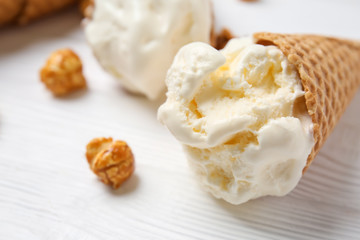 Waffle cone with delicious ice cream on white table, closeup