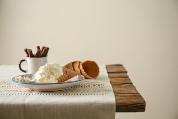 Waffle cone with delicious ice cream on wooden table