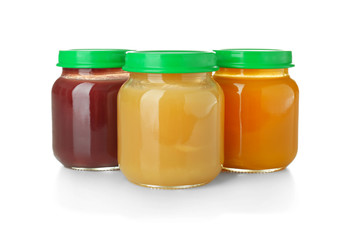 Glass jars with healthy baby food on white background
