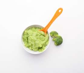 Bowl with healthy broccoli puree for baby on white background, top view