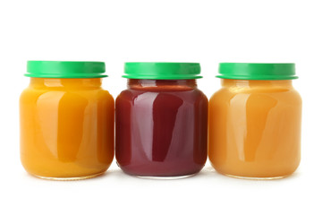 Glass jars with healthy baby food on white background